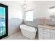 Modern bathroom featuring a freestanding tub under a window and a marble countertop vanity at 882 Bay Point Dr, Madeira Beach, FL 33708