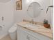 Bathroom featuring a round mirror, vanity, and modern toilet at 882 Bay Point Dr, Madeira Beach, FL 33708