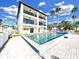 Amazing three-story home featuring a pool, balconies, turf lawn, and a serene waterfront view at 882 Bay Point Dr, Madeira Beach, FL 33708
