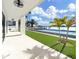 Outdoor space featuring a pool, artificial grass, covered patio, and serene waterfront views at 882 Bay Point Dr, Madeira Beach, FL 33708