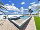 Beautifully designed backyard featuring a modern pool, a spa, waterfront views, and lush turf at 882 Bay Point Dr, Madeira Beach, FL 33708