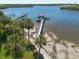 Gorgeous aerial view of a waterfront property featuring a private dock and clear blue waters, surrounded by lush palm trees at 8820 S Hickory Ln, Riverview, FL 33578