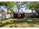 A small shed sits in the middle of a grassy backyard surrounded by a white fence and mature trees at 8820 S Hickory Ln, Riverview, FL 33578