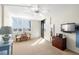 Primary bedroom with a ceiling fan, a mounted TV, shuttered windows, and access to a balcony at 9415 Blind Pass Rd # 704, St Pete Beach, FL 33706