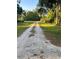 Long gravel driveway leading to a secluded property surrounded by lush greenery and mature trees on a sunny day at 7006 41St E Ave, Bradenton, FL 34208