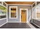 Beautiful covered front porch with a wooden door, complemented by natural light and wood flooring at 114 E Emily St, Tampa, FL 33603