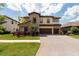 Gorgeous two-story home with brick accents, a three-car garage, and lush landscaping at 11966 Climbing Fern Ave, Riverview, FL 33579