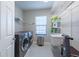 Well-lit laundry room with washer, dryer, sink, and shelving for organized storage at 11966 Climbing Fern Ave, Riverview, FL 33579