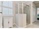 Neutral bathroom with a modern glass shower, shuttered window, and sleek white cabinet at 12379 Amica Loop, Venice, FL 34293