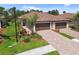 Charming home featuring a tile roof, brick driveway, and lush landscaping with palm trees at 12379 Amica Loop, Venice, FL 34293