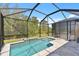 Screened-in swimming pool area featuring clear water, stone flooring, and lush green landscaping at 12379 Amica Loop, Venice, FL 34293