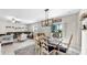 Open-concept dining area with a farmhouse-style table and views of the adjacent living area and sliding glass doors at 12841 Wildflower Meadow Dr, Riverview, FL 33579