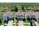 Aerial view of three homes with landscaped lawns and driveways surrounded by lush trees in the background at 12841 Wildflower Meadow Dr, Riverview, FL 33579