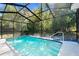 Private screened-in pool and patio area surrounded by lush landscaping and a clear blue sky at 13501 Whitby Rd, Hudson, FL 34667