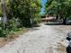 View of a large gravel parking area and the home's red accented screened porch at 14633 Sassandra Dr, Odessa, FL 33556