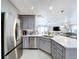 Close-up of the kitchen featuring stainless steel appliances, gray cabinetry, and quartz countertops at 15407 Quail Woods Pl, Ruskin, FL 33573