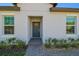 Home featuring a gray front door flanked by windows and enhanced by brick pavers and manicured bushes at 16710 Shell Bay Dr, Land O Lakes, FL 34638