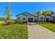 Charming single-story home with a well-manicured lawn, paver driveway, and mature landscaping at 16710 Shell Bay Dr, Land O Lakes, FL 34638