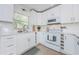 Bright kitchen with white cabinets, white subway tile backsplash, stainless steel appliances, and a window overlooking the yard at 2261 Queen S St, St Petersburg, FL 33712
