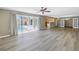 Open living room with wood flooring, ceiling fan, and sliding glass doors to the screened-in pool at 2312 Heron Cir, Clearwater, FL 33762