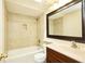 Bright bathroom featuring a shower-tub combo, tiled surround, and a modern vanity with a stylish mirror at 3103 Taragrove Dr, Tampa, FL 33618