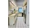 Galley kitchen with white appliances, matching cabinetry and white tile flooring at 3629 Indigo Pond Dr # 3629, Palm Harbor, FL 34685