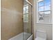 Bathroom features a shower-over-tub with glass doors, tiled walls, and window with natural light at 4310 W Sevilla St, Tampa, FL 33629
