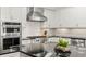 Close up of the kitchen island, featuring black countertops, mosaic backsplash, and stainless range hood at 4310 W Sevilla St, Tampa, FL 33629