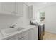 Well-lit laundry room featuring sleek white cabinetry, sink, and modern washer and dryer appliances at 4310 W Sevilla St, Tampa, FL 33629