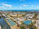 Aerial view showcases tennis courts and residential properties along the coast on a bright, sunny day at 438 62Nd St, Holmes Beach, FL 34217
