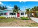Inviting home with a well-maintained lawn, complemented by a bright red door and shutters at 438 62Nd St, Holmes Beach, FL 34217