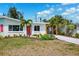 Charming home with a vibrant red door, complemented by lush landscaping at 438 62Nd St, Holmes Beach, FL 34217