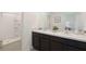 Bathroom featuring double sinks with granite counters, dark cabinets, and a tub shower at 526 Mangrove Shade Cir, Apollo Beach, FL 33572