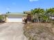 Front exterior of home featuring a green metal roof, 2-car garage, and palm trees at 540 115Th Ave, Treasure Island, FL 33706