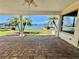 Covered patio with brick flooring, pillars, and a view of the waterfront with palm trees at 540 115Th Ave, Treasure Island, FL 33706