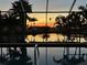 Relaxing pool area with a screened enclosure overlooking a tranquil pond and palm trees at sunset at 6181 9Th Avenue Ne Cir, Bradenton, FL 34212