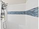 Walk-in shower featuring white tiled walls accented with a decorative blue tile border at 6181 9Th Avenue Ne Cir, Bradenton, FL 34212