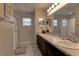 Bathroom with double sink vanity, large mirror, walk-in shower with glass doors, and neutral decor at 6632 Laxey Ct, Zephyrhills, FL 33541