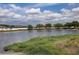 Scenic view of a tranquil pond lined with lush green trees and reeds under a partly cloudy sky at 6632 Laxey Ct, Zephyrhills, FL 33541