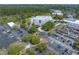 Overhead view of a large modern building, a parking lot, mature trees, and lush landscaping, a pond and other commercial buildings at 9044 Lynwood Dr, Seminole, FL 33772