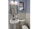 Cozy bathroom featuring a pedestal sink, matching toilet, and a framed mirror illuminated by modern sconces at 9044 Lynwood Dr, Seminole, FL 33772
