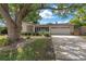 Charming single-story home featuring a two-car garage, lush landscaping, and a covered front porch framed by a mature shade tree at 9044 Lynwood Dr, Seminole, FL 33772