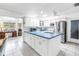 Open kitchen with white cabinetry, blue countertops, stainless steel appliances, and adjacent living area at 9044 Lynwood Dr, Seminole, FL 33772