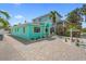 Charming turquoise home with lush landscaping, brick driveway, and a serene tropical atmosphere on a sunny day at 106 23Rd Ave, St Pete Beach, FL 33706
