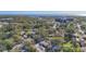 Expansive aerial view of a neighborhood with tree coverage and water in the distance, offering a sense of community at 1201 Kapok Kove Cir, Clearwater, FL 33759