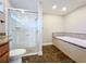 Bright bathroom featuring tiled floors, a walk-in shower with glass doors, and a soaking tub with decorative tile surround at 1201 Kapok Kove Cir, Clearwater, FL 33759