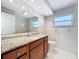 Bright bathroom featuring a granite vanity, framed mirror, toilet, window and tub at 1201 Kapok Kove Cir, Clearwater, FL 33759