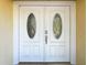 Close-up view of elegant white double doors with decorative glass, offering a welcoming entrance at 1201 Kapok Kove Cir, Clearwater, FL 33759