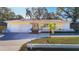 Charming yellow single-story home featuring a red tile roof and double-door entryway, showcasing its curb appeal at 1201 Kapok Kove Cir, Clearwater, FL 33759