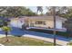 Exterior view of the home with a two-car garage, a red tiled roof and mature landscaping at 1201 Kapok Kove Cir, Clearwater, FL 33759